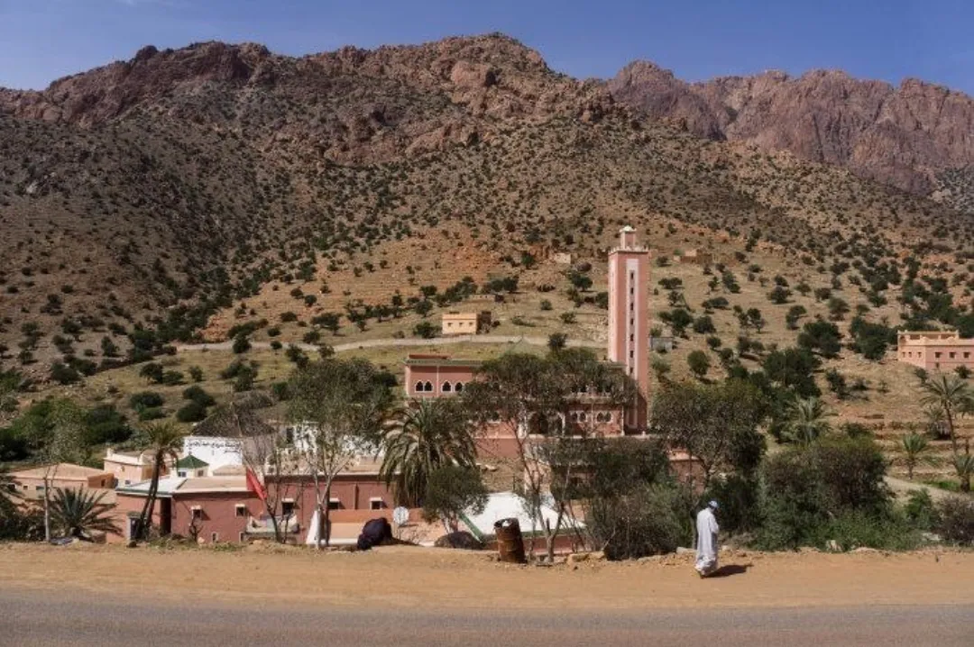 Mosque with a tall minaret at the foot of arid rocky mountains