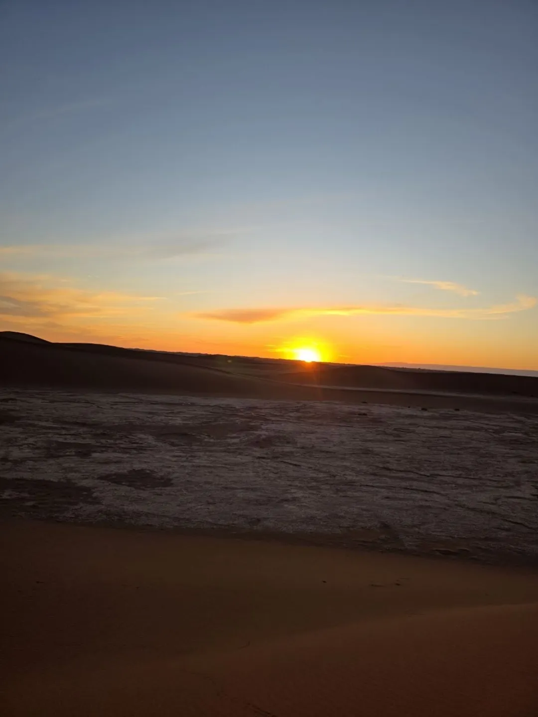 Sunset over desert dunes and a flat sandy plain