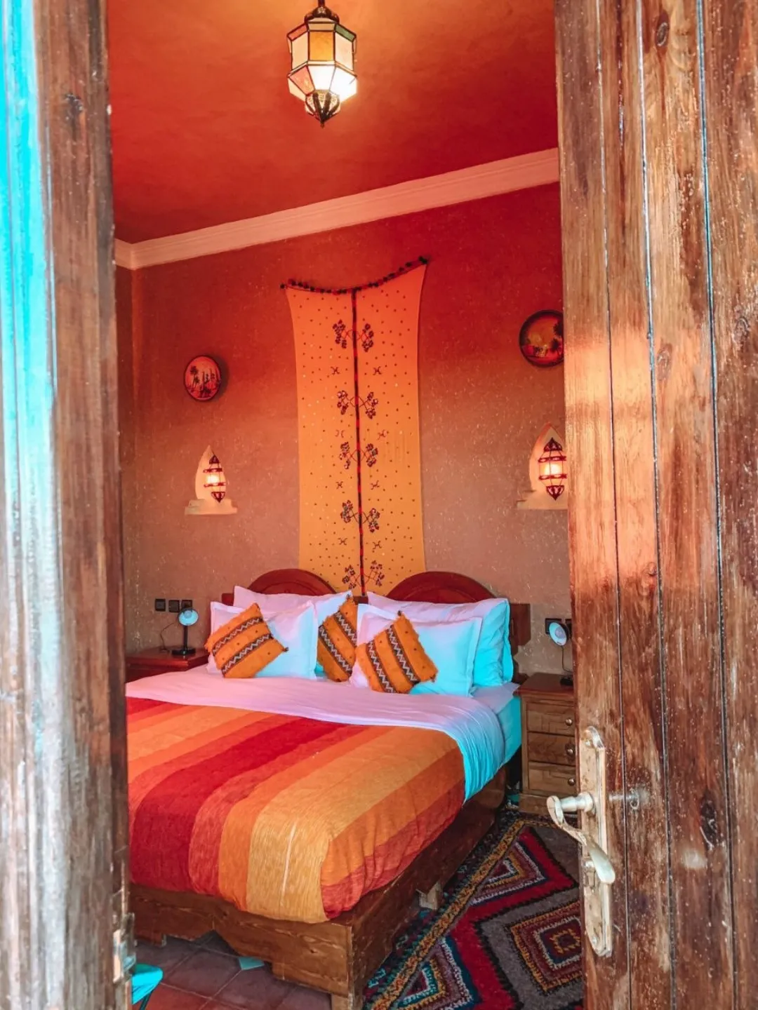Warm Moroccan-style bedroom with colorful bedding seen through wooden doors